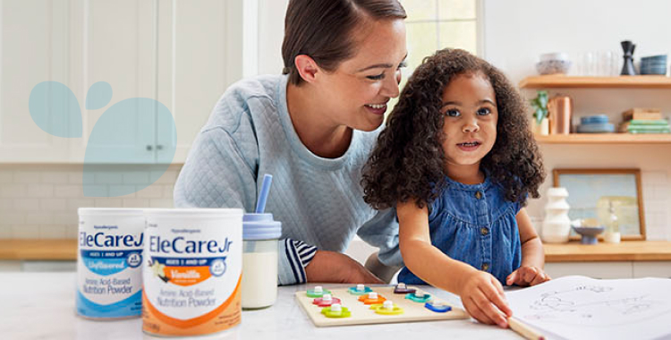 A young girl and her mom at the kitchen island with a puzzle, with EleCare Jr Unflavored and EleCare Jr Vanilla in front.