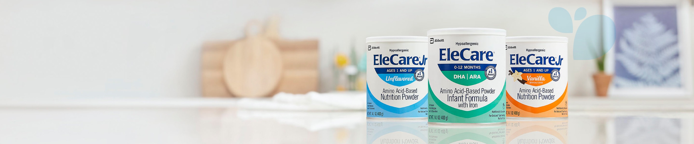 Cans of EleCare Jr Unflavored, EleCare Infant Formula, and EleCare Jr Vanilla sitting on a kitchen counter.